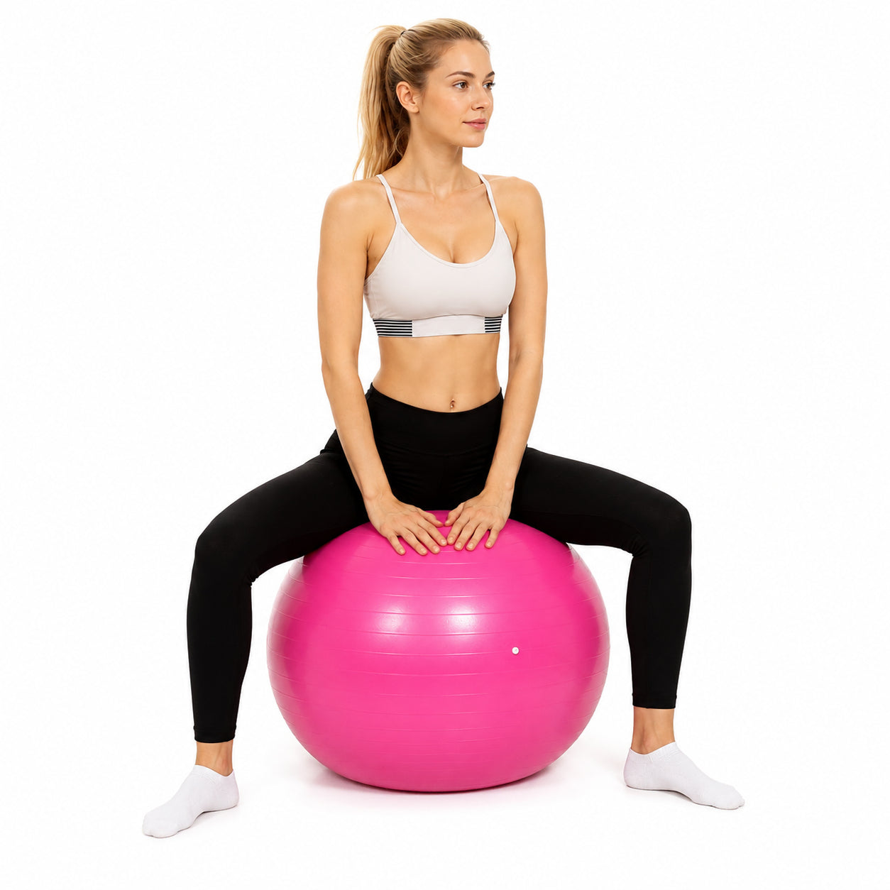 Kvinna sitter på rosa pilatesboll mot vit bakgrund.